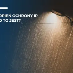Lampa uliczna świeci w deszczu. Tekst informuje, co oznacza stopień ochrony IP66, czyli wysoką odporność na pył i wodę.