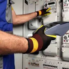 Technik w rękawicach obsługuje licznik energii elektrycznej, przygotowując dokumentację do Tauron reklamacje.